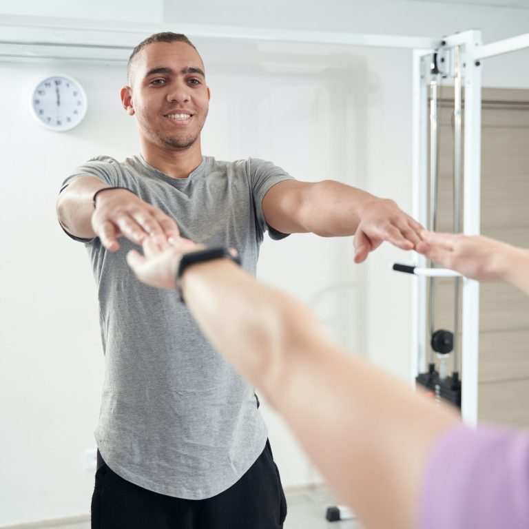 Cheerful man doing physiotherapy exercise in clinic